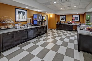 A hotel breakfast area with a checkered floor, a coffee station, and various food dispensers. - Hampton Inn & Suites Ada (Ada)