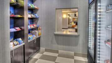 A corridor with snack shelves and a refrigerator.