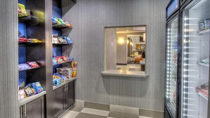 A hotel corridor with snack shelves, a mirror, and a refrigerator. - Hampton Inn & Suites Ada (Ada)
