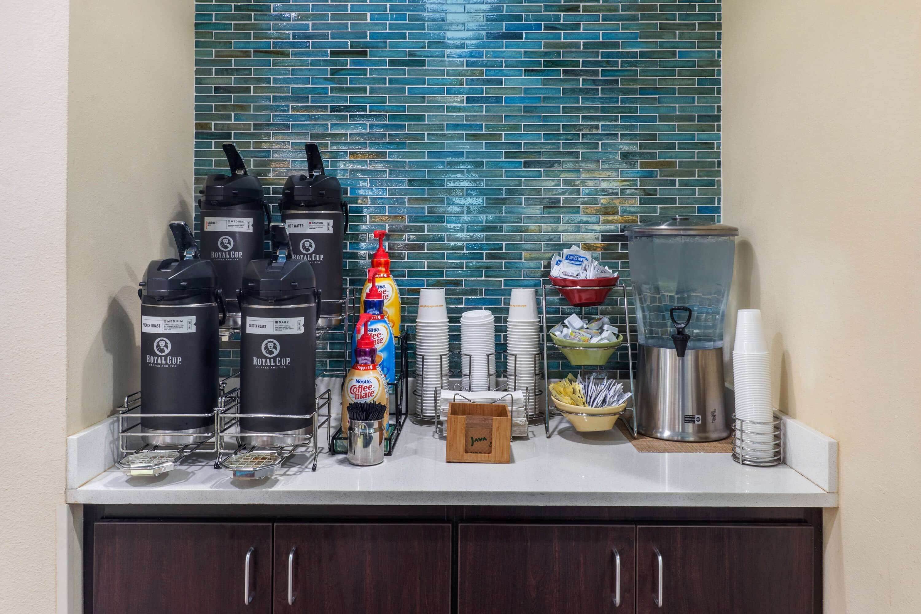 A hotel breakfast bar with coffee makers, a coffee station, and a water dispenser.