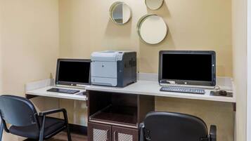 A hotel room with two HP desktop computers, a printer, and two chairs.