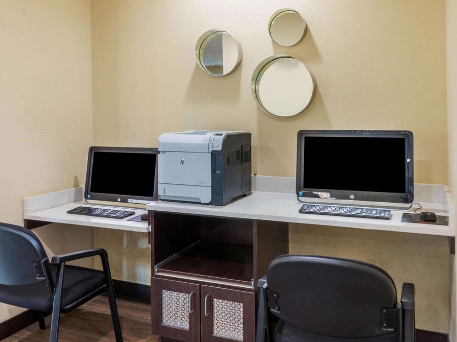 A hotel room with two HP desktop computers, a printer, and two chairs.