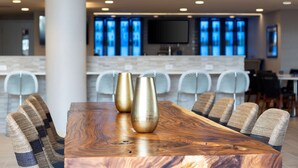 Un espace repas moderne avec une table en bois, deux vases dorés et six chaises rembourrées.