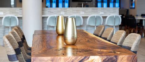 A modern dining area with a wooden table, two gold vases, and six upholstered chairs.