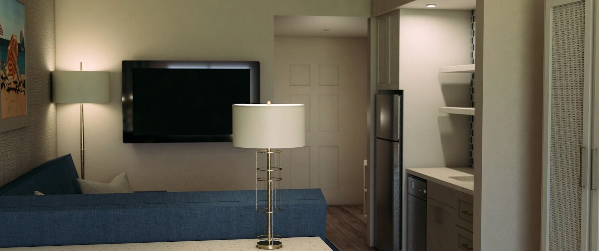 Una sala moderna con un sofá azul, una lámpara de pie, un televisor de pantalla plana y una zona de cocina con refrigerador y armarios.