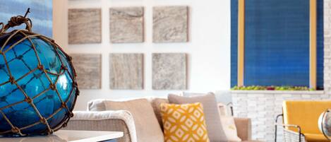 A living room with a blue globe ornament, a sofa with patterned cushions, and a wall with square artwork.