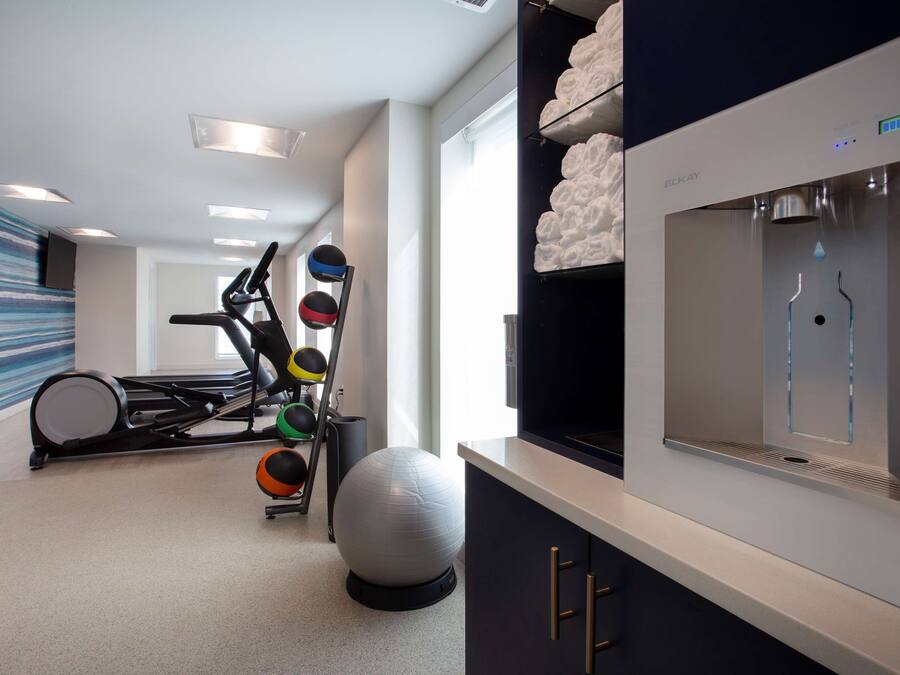 Un gimnasio en casa con equipo de ejercicio, una pelota grande para hacer ejercicio y un dispensador de agua.