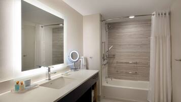 A modern bathroom with a large mirror, two sinks, a shower, and a bathtub.