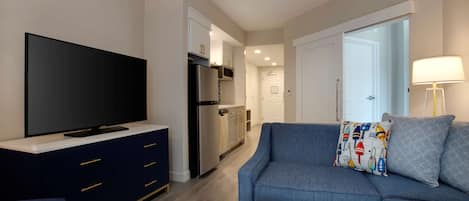 A modern living room with a flat-screen TV, dark blue sofa, and a patterned pillow.