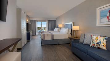 Une chambre d’hôtel équipée d’un lit, d’un canapé, d’une télévision, d’un bureau et offrant une vue sur l’extérieur.