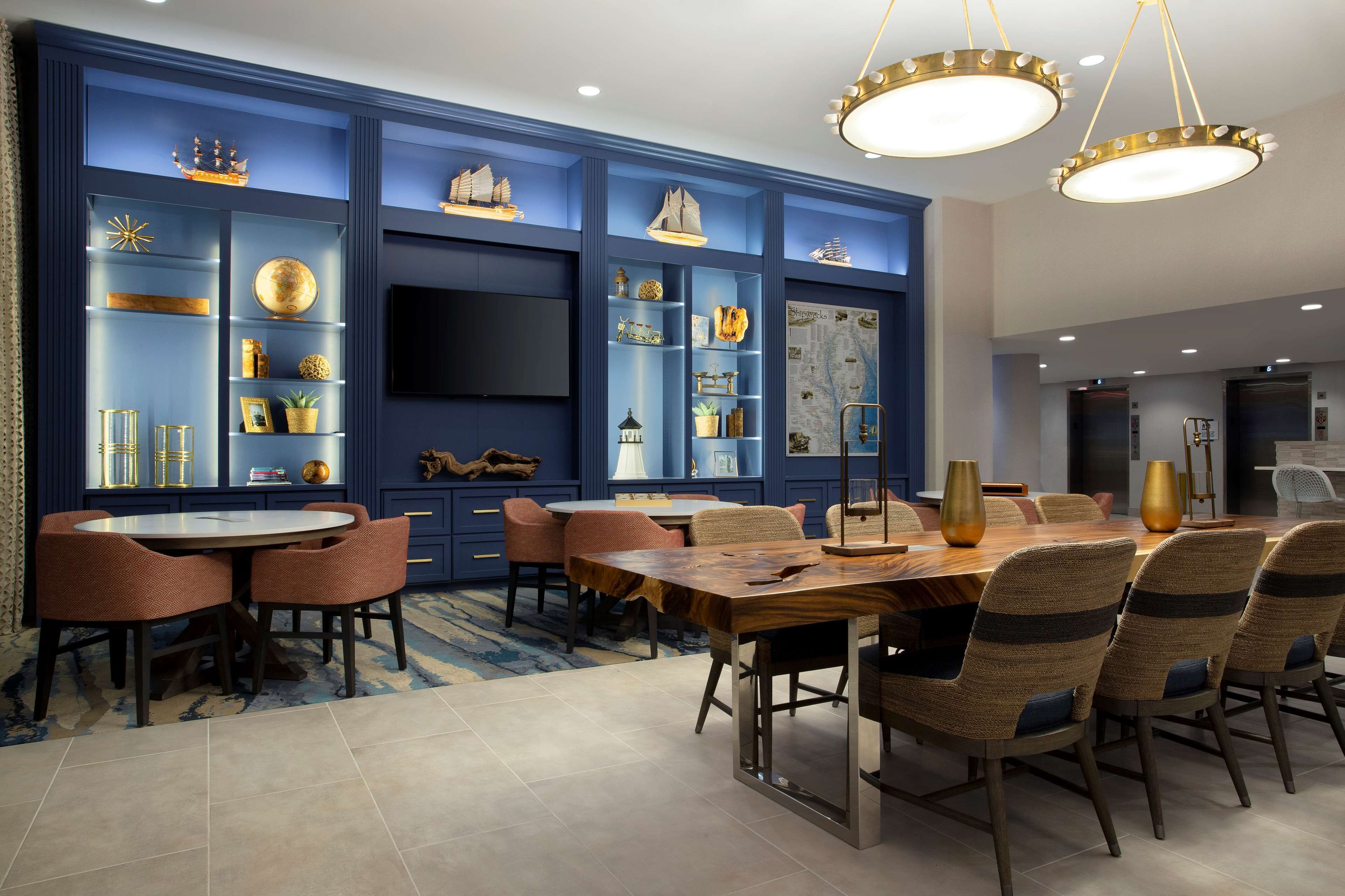 Un comedor moderno con una mesa redonda y sillas, paredes de acento azul y estantes decorativos.