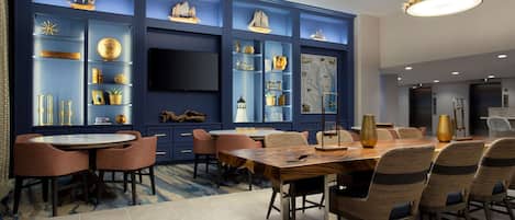 A modern dining area with a round table and chairs, blue accent walls, and decorative shelves.