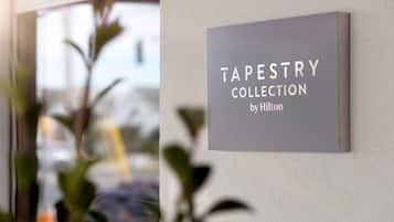 Ein Schild an der Wand mit der Aufschrift 'TAPESTRY COLLECTION by Hilton'.