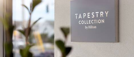 Un letrero en una pared que dice 'TAPESTRY COLLECTION by Hilton'.