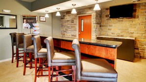 Una zona de bar con pared de piedra, una puerta de madera y un televisor de pantalla plana sobre el mostrador.