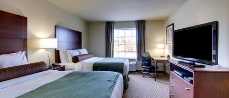 A hotel room with two beds, a desk, a television, and a dresser.
