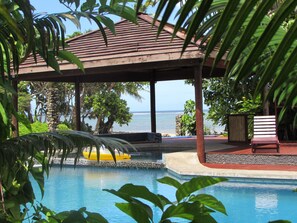 A pool area with a wooden gazebo, a yellow float, and a view of the ocean. - deVos - The Private Residence (Korolevu)