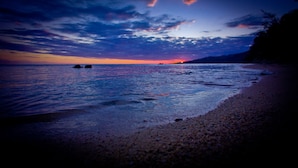 Una playa con aguas tranquilas y un atardecer.