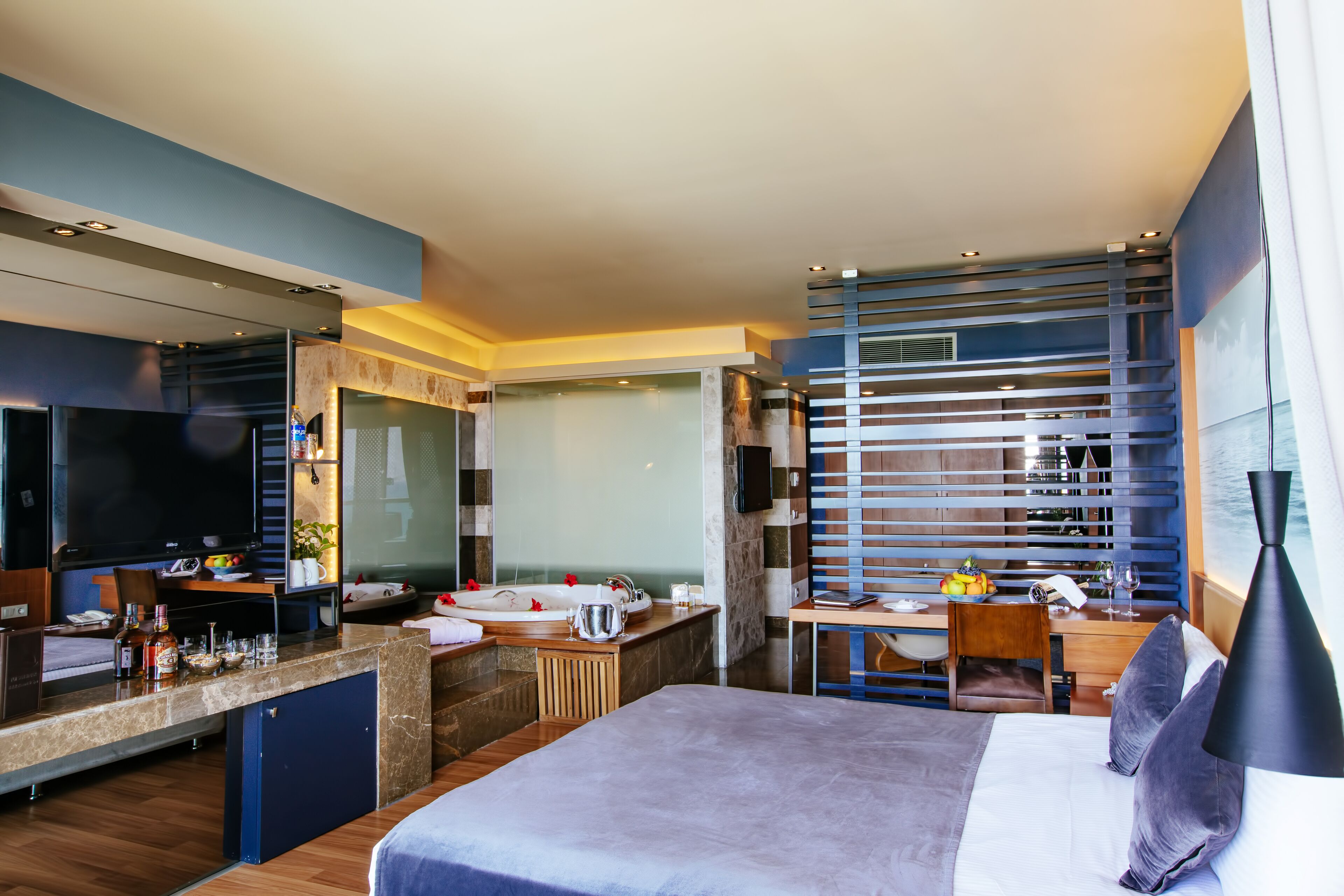 Una habitación de hotel moderna con una cama grande, un escritorio, un baño y un televisor.