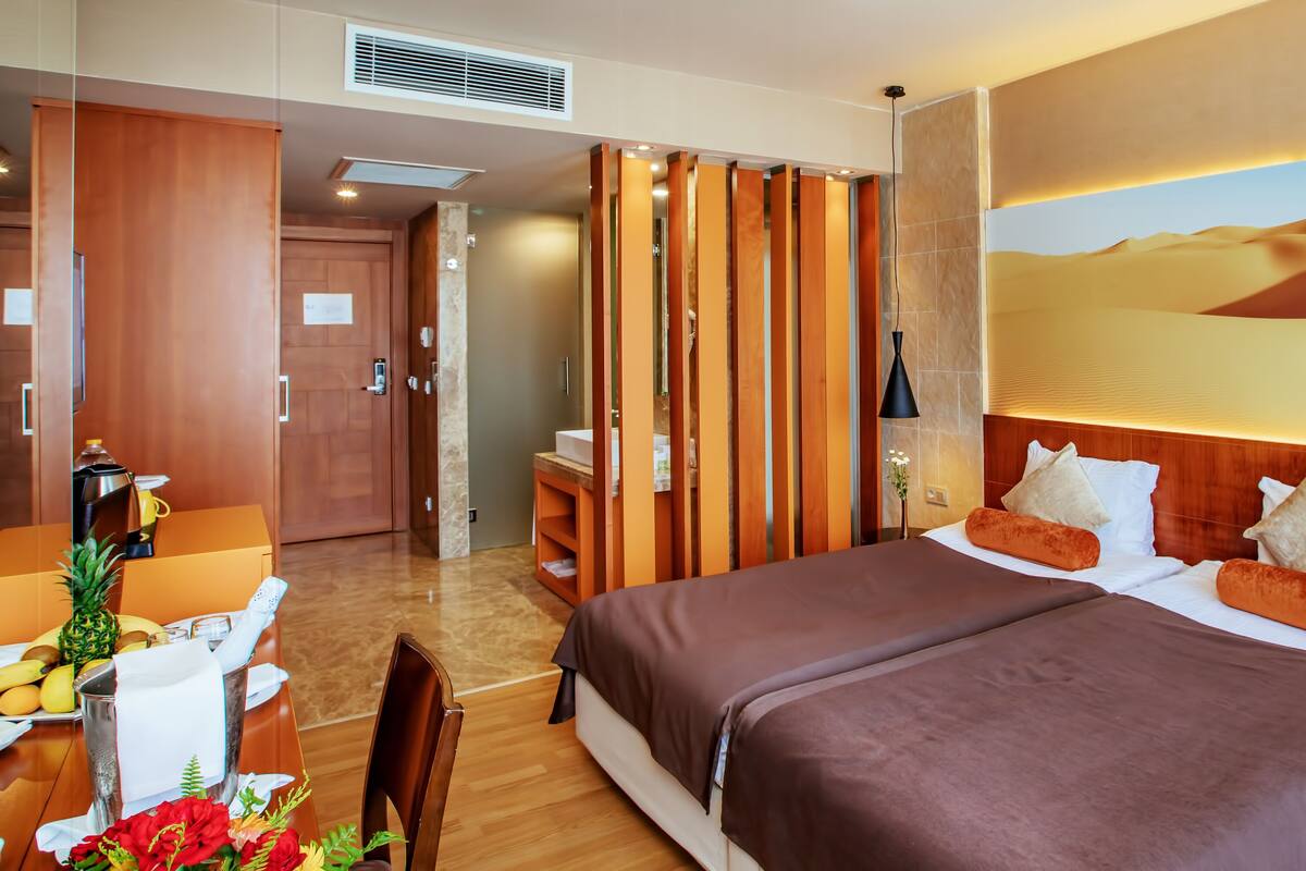 Ein Hotelzimmer mit einem großen Bett, einem Schreibtisch mit Kaffeemaschine und einem Wandbild im Wüstendesign.