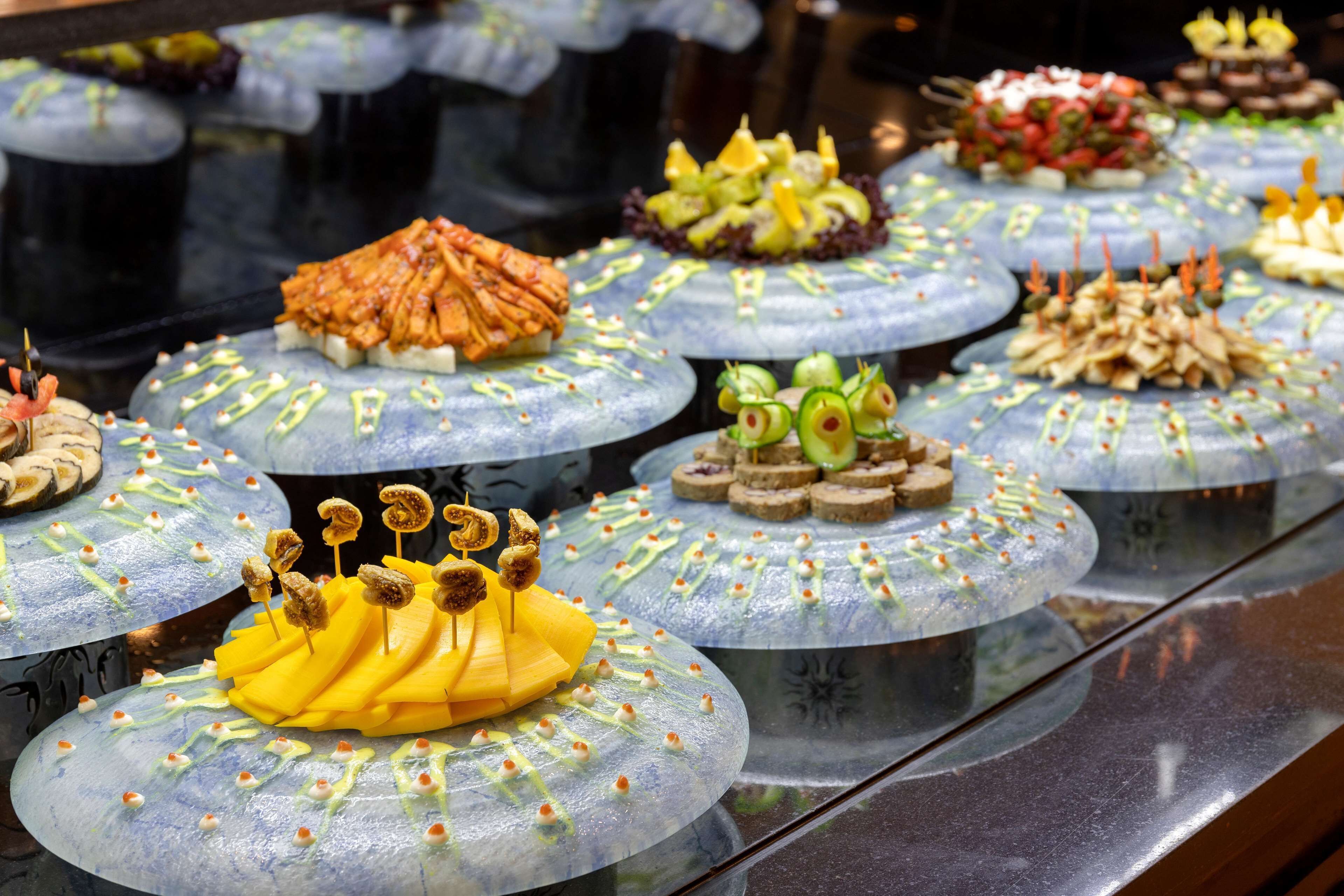 Une variété de plats présentés sur des assiettes rondes et transparentes, agrémentées d’éléments décoratifs.