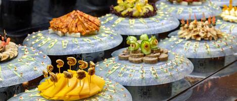 A variety of food items displayed on round, transparent plates with decorative elements.