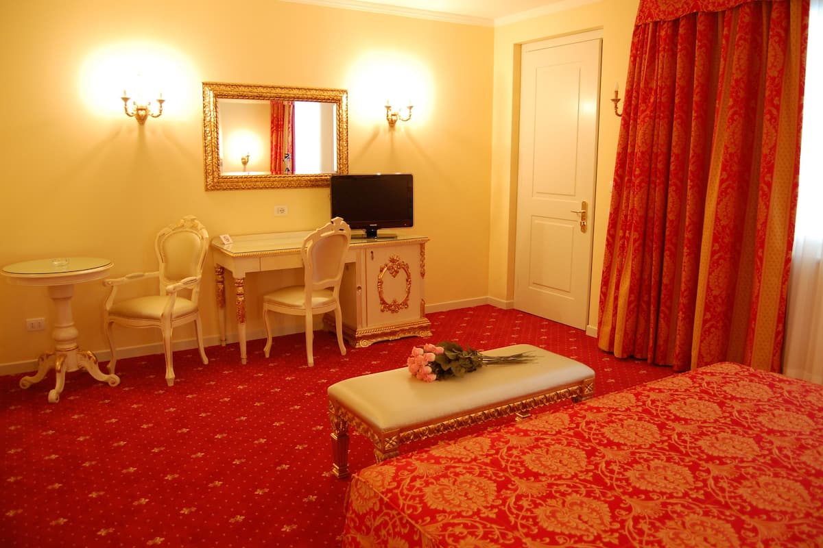 A hotel room with a desk, chair, and a television.