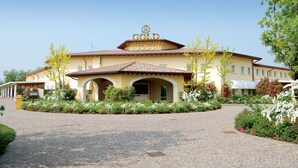 Un hôtel appelé « Gold Hotel Motel », doté d’un toit en tuiles, d’une entrée en arc de cercle et d’un jardin aménagé à l’avant.