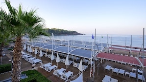 Um resort à beira-mar com espreguiçadeiras, guarda-sóis e vista para o mar.