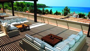 Terraço no telhado com um conjunto de sofás, uma mesa pequena e vista para o mar.