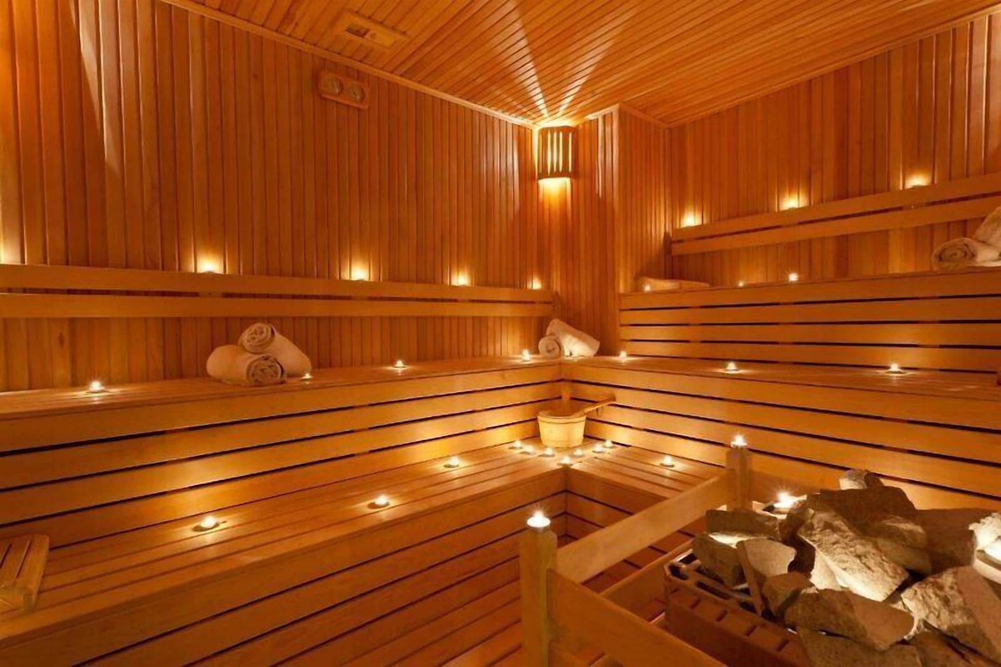 A sauna with wooden benches, candles, and rocks.