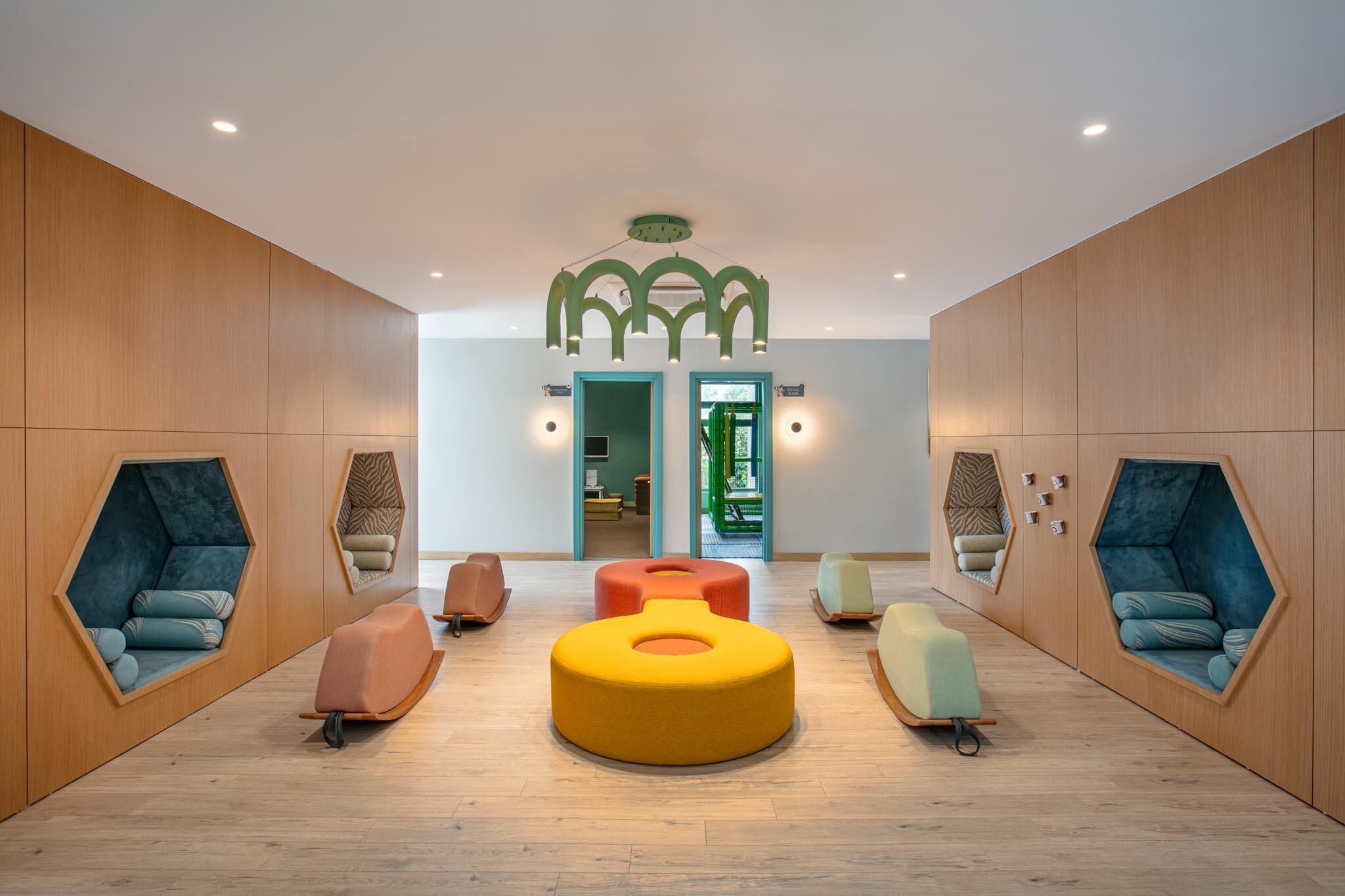 A modern interior with hexagonal seating areas, wooden walls, and a central light fixture.