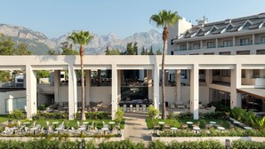 A hotel with a central courtyard featuring outdoor seating, palm trees, and a view of mountains.