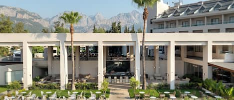 A hotel with a central courtyard featuring outdoor seating, palm trees, and a view of mountains.