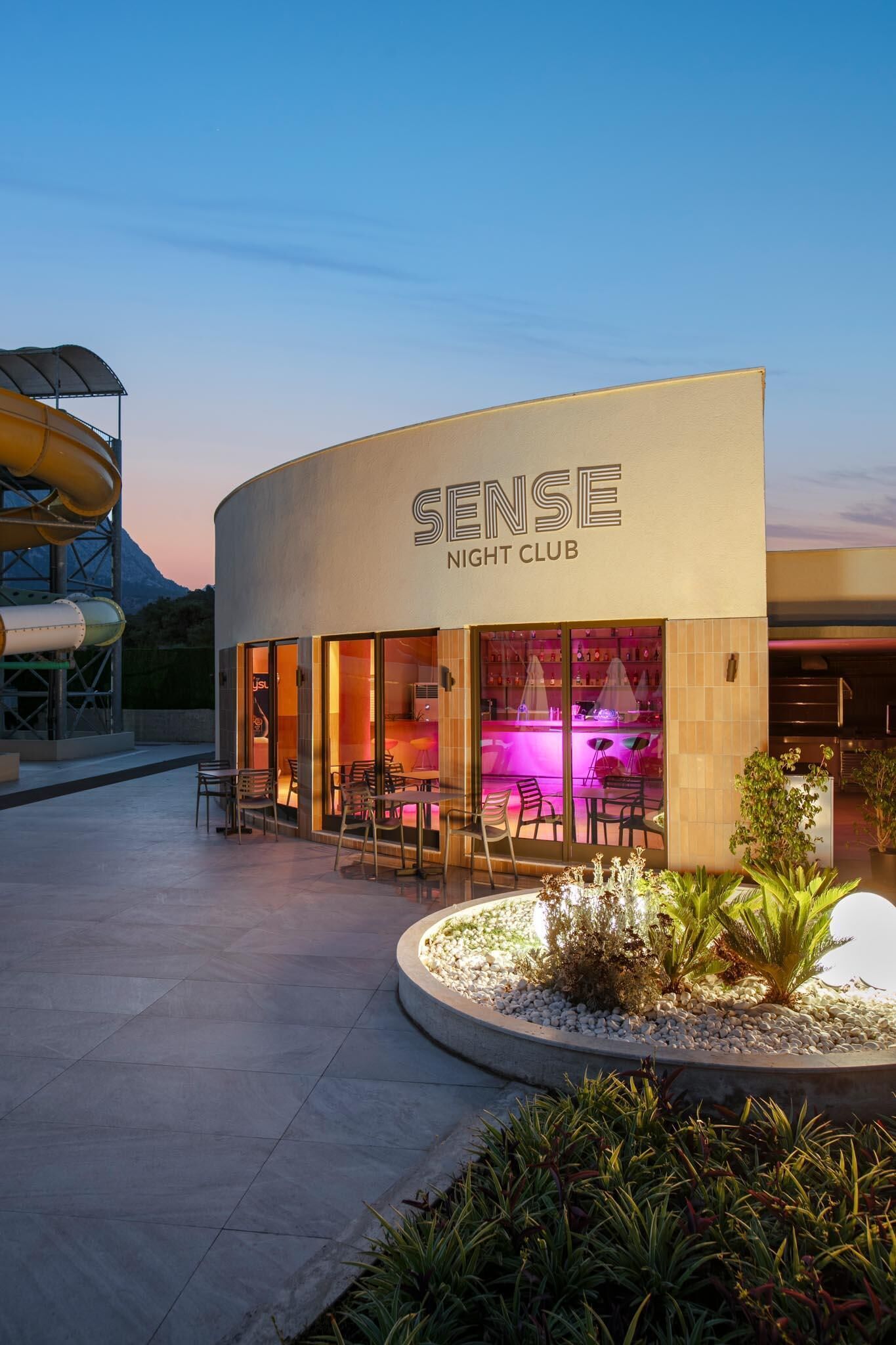 A modern building with a sign reading 'SENSE NIGHT CLUB' and outdoor seating.