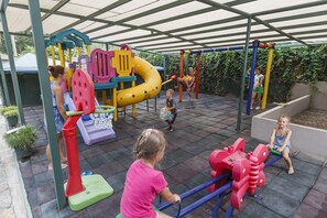 Un parque infantil con diversas estructuras de juego, como toboganes, columpios y un balancín.