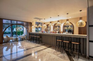 Un área de bar moderna con piso de mármol pulido, taburetes de mimbre e iluminación colgante.