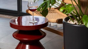 Ein gemütlicher Innenbereich mit Tisch und Stühlen, einer Topfpflanze und einem Glas Wein.