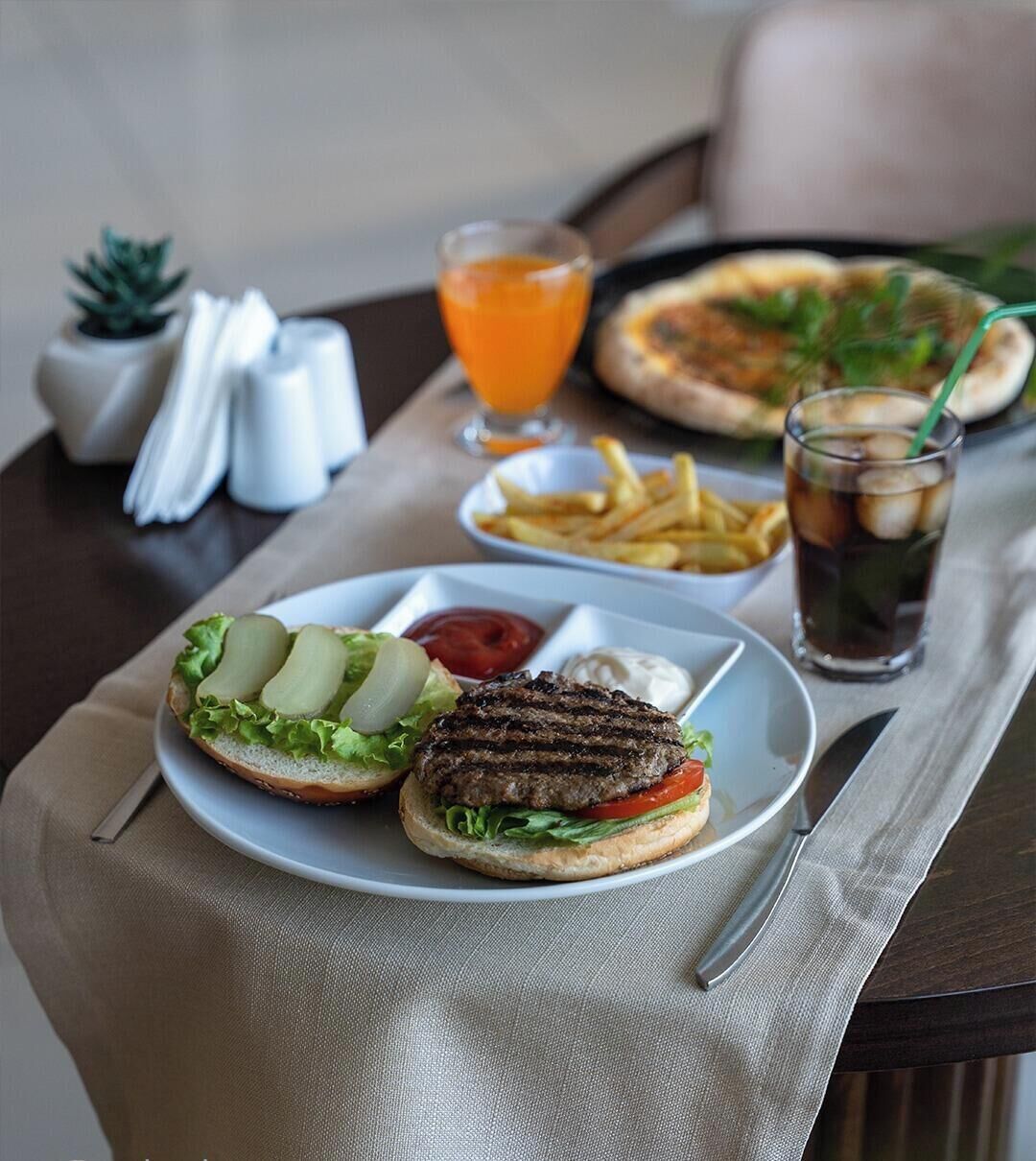Un repas composé d’un hamburger, de frites et d’une boisson, servi sur une table.