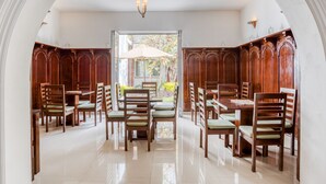 A dining area with wooden paneling, a central table with chairs, and a view through an arched doorway. - Quinta Allende (Querétaro)
