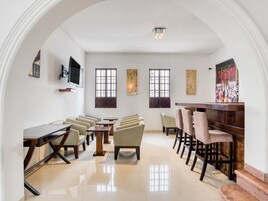 Un salón de conferencias con una larga mesa, varias sillas, un televisor montado en la pared y ventanas amplias.