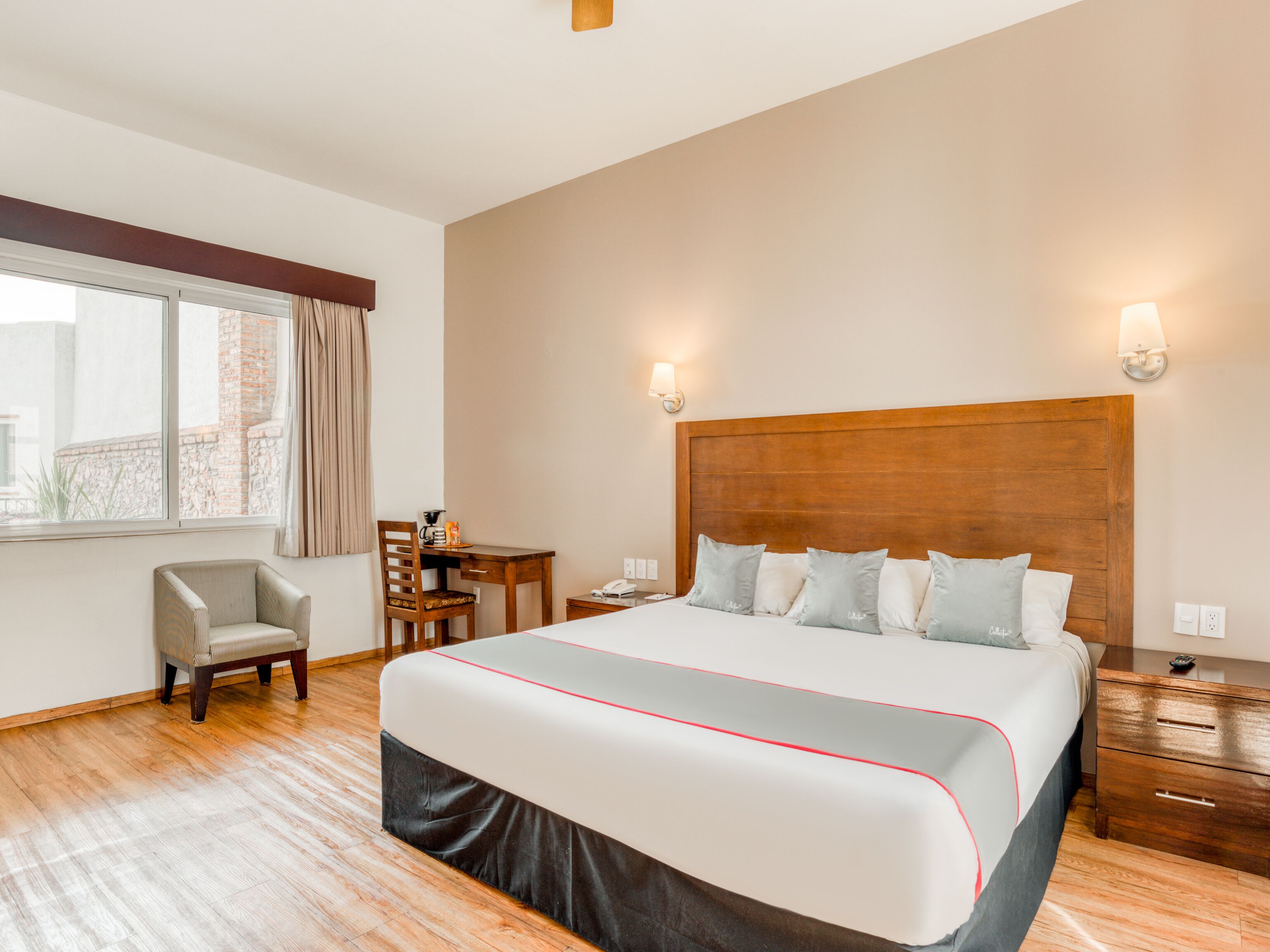 Une chambre d’hôtel avec un grand lit, un bureau, une chaise et une fenêtre avec des rideaux.