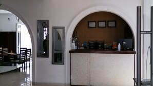A modern reception area with a polished floor, a round dining table, and a counter with a decorative mirror. - Quinta Allende (Querétaro)