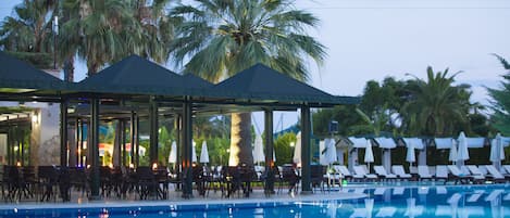 Una piscina techada, una piscina al aire libre, sombrillas