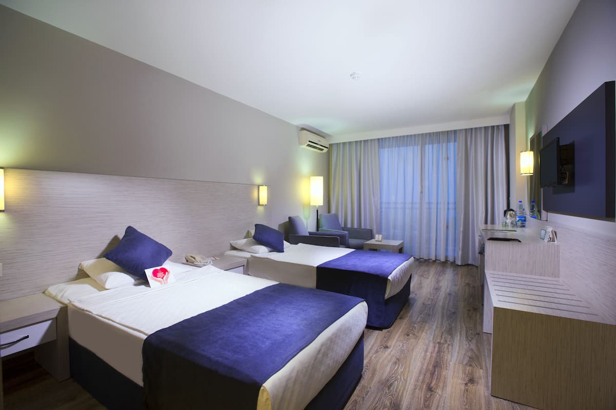 A hotel room with two beds, a desk, a TV, and a minibar.