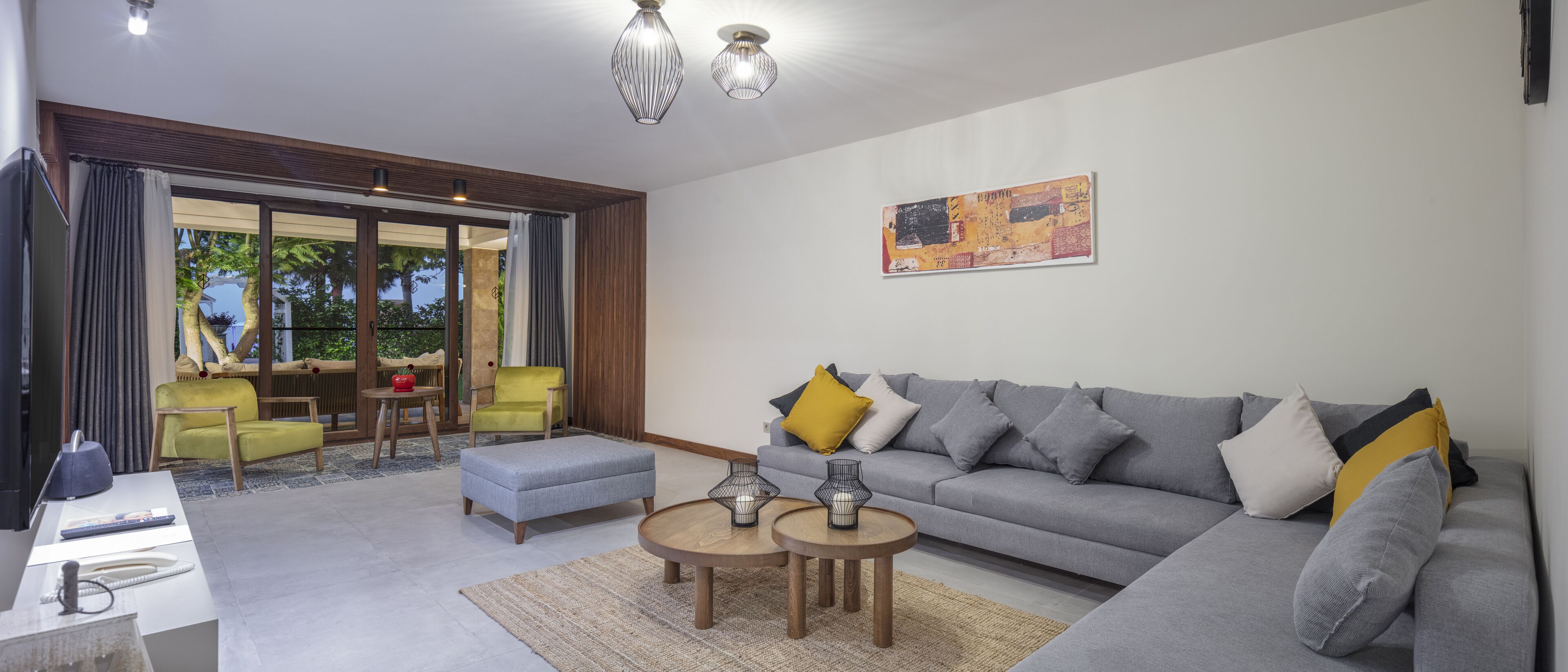 A modern living room with a grey sofa, yellow and white cushions, a coffee table, and a TV.