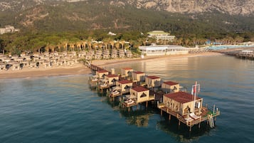 Een kusthotel met bungalows boven het water, verbonden door een houten looppad.
