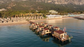 Een kusthotel met bungalows boven het water, verbonden door een houten looppad.