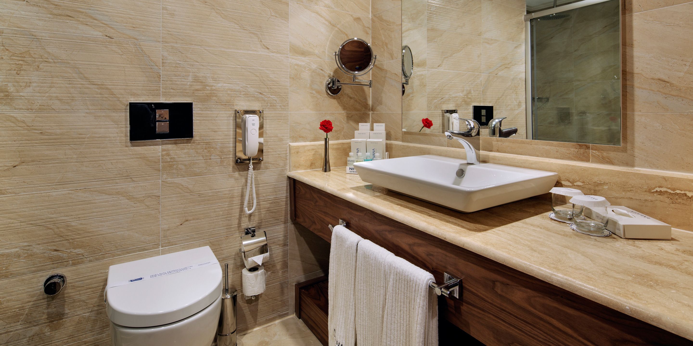 A modern bathroom with a toilet, sink, vanity, mirror, and towel rack.