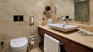 A modern bathroom with a toilet, sink, vanity, mirror, and towel rack.